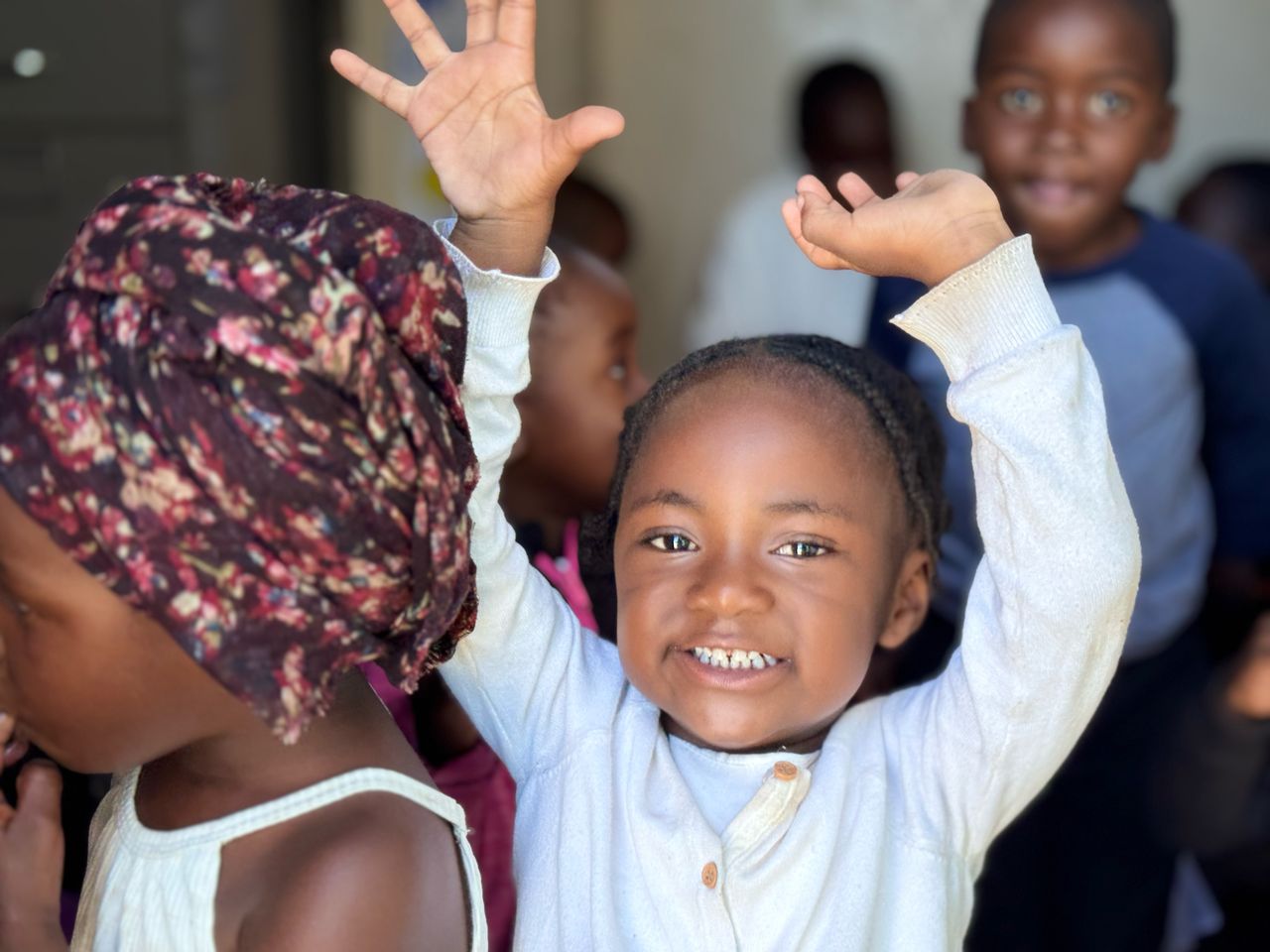 Zambian student joyfully raising hands in a classroom
